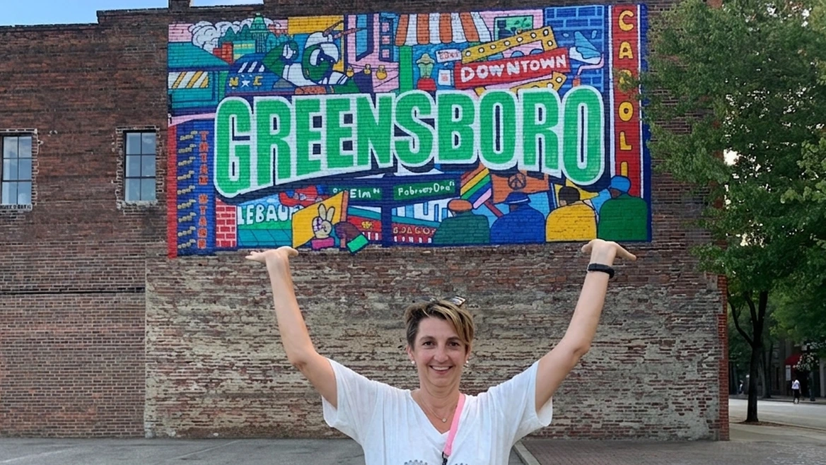 a woman pretending to hold the Greensboro mural