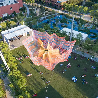 a fishing net sculpture hanging over a park