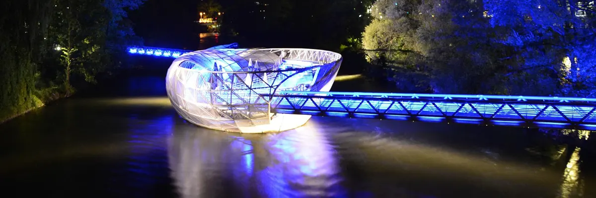 Graz amphitheater on the river lit up at night