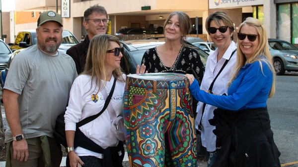 a group of people standing around a painted jeans sculpture